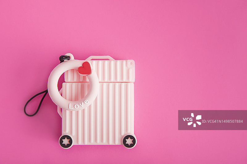 粉色背景上的粉色行李箱特写，带有救生圈上的Love字样和复制空间图片素材