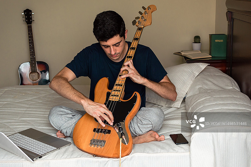 年轻男人在家使用电脑练习吉他图片素材