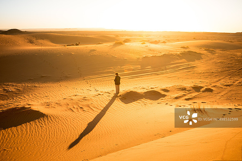 日出时分，独自一人在沙漠沙丘中的女人图片素材