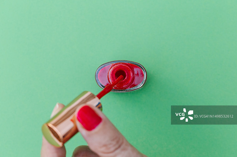 红色美甲的女人手指，绿色背景图片素材