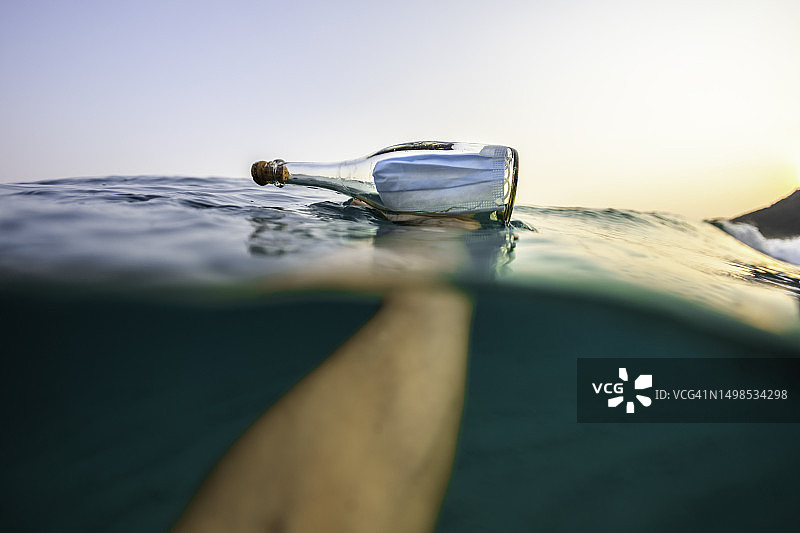 手持海中玻璃瓶内的新冠医用口罩图片素材