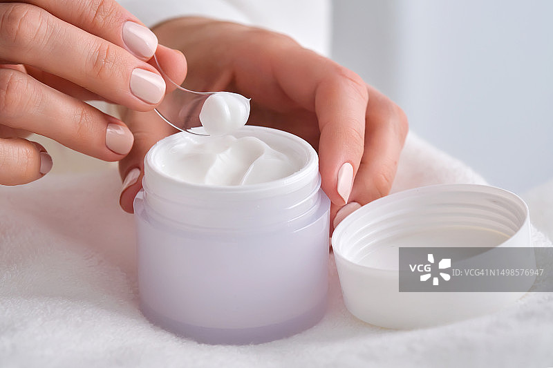 女人拿着一罐白色面霜图片素材