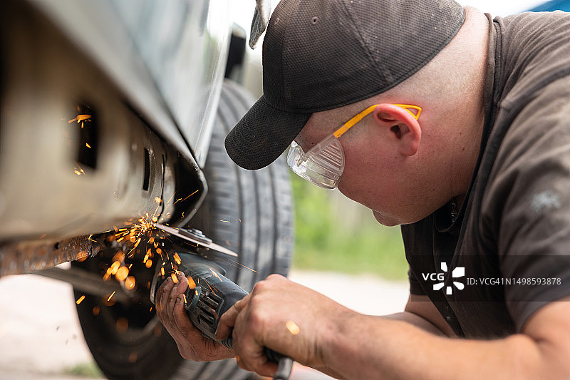 汽车修理工切割汽车门槛上的锈蚀零件图片素材