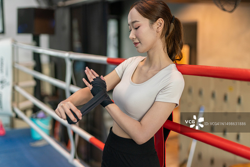 亚洲女拳击手在拳击锻炼前在拳击馆做手部缠绕图片素材
