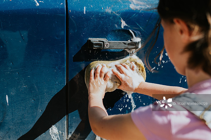 儿童清洗汽车上的鸟粪和泥土图片素材