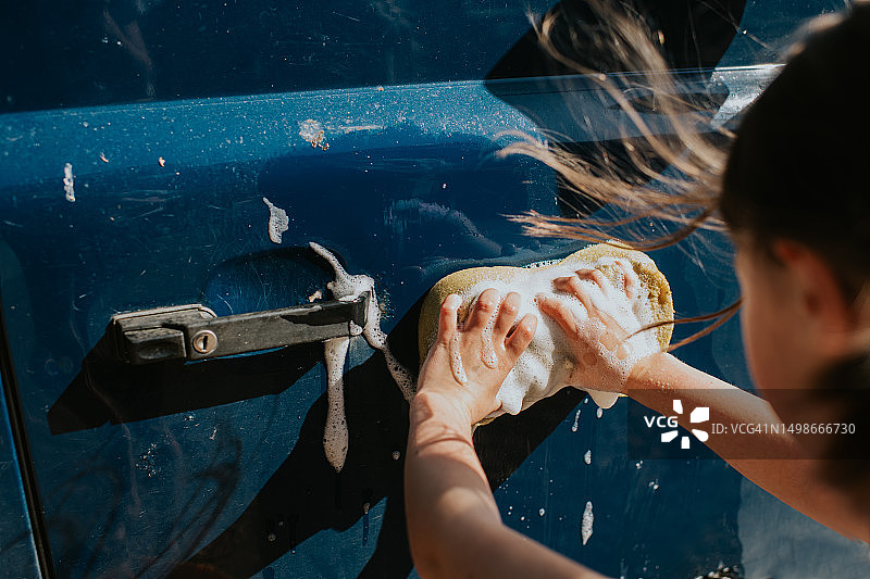儿童清洗汽车上的鸟粪和泥土图片素材