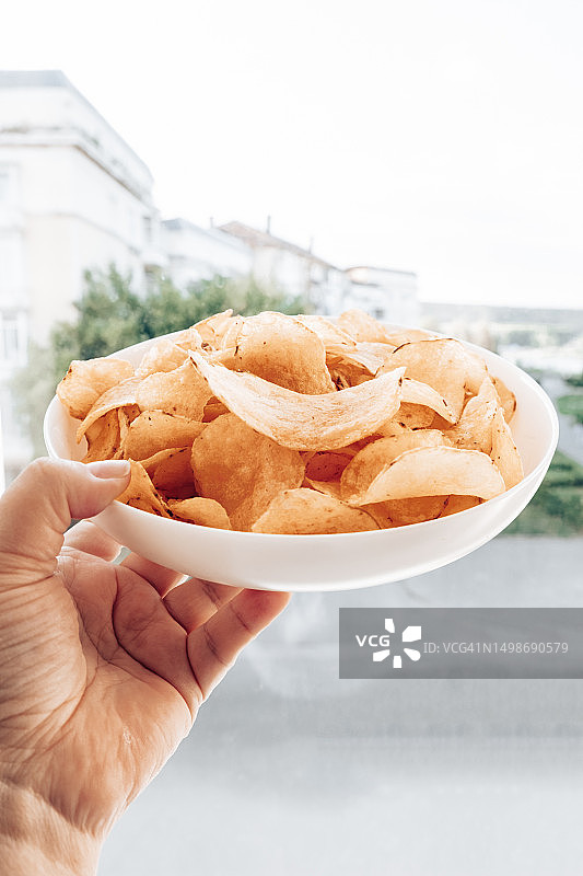 手拿薯片，碗里的土豆片图片素材