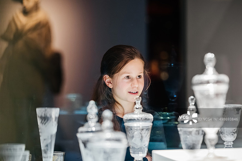 年轻女孩凝视着玻璃柜中展示的博物馆古董图片素材