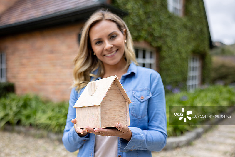 快乐的女人拿着一个房屋模型 - 房地产概念图片素材
