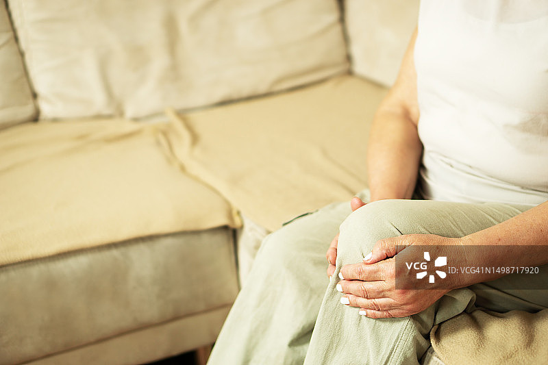 在家坐在沙发上膝盖疼痛的女人腰部特写图片素材