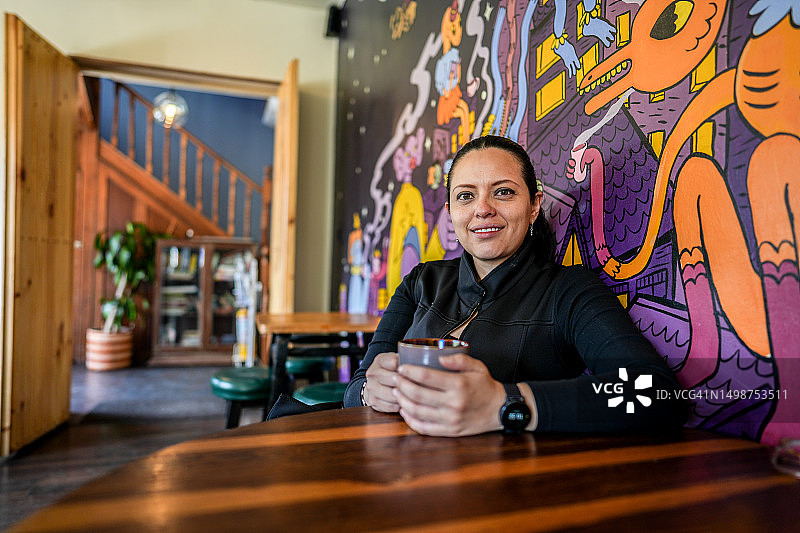 中年女人在咖啡店里拿着马克杯的肖像图片素材