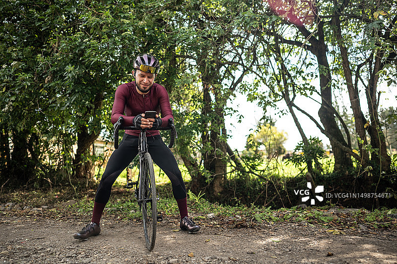 骑行男人在小路上使用手机图片素材