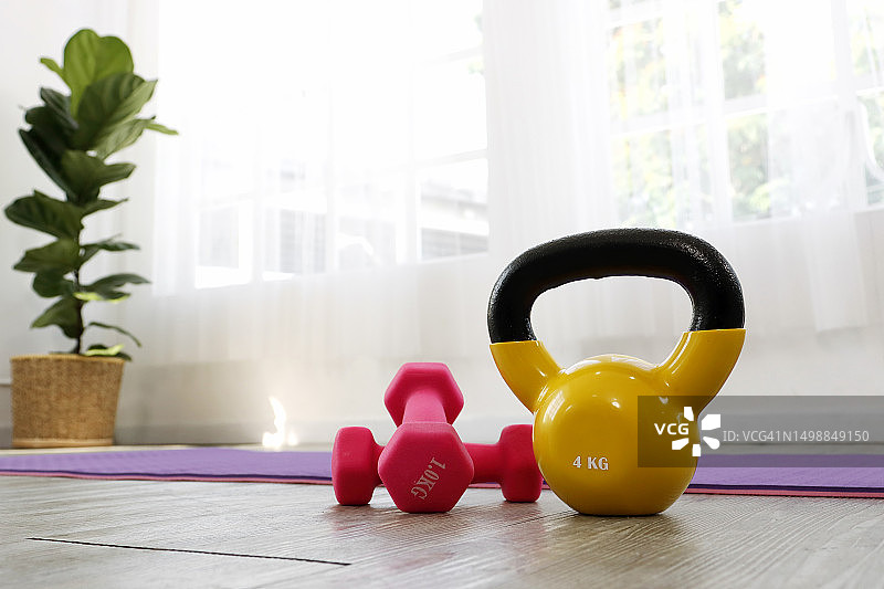 客厅瑜伽垫上的壶铃和杠铃图片素材