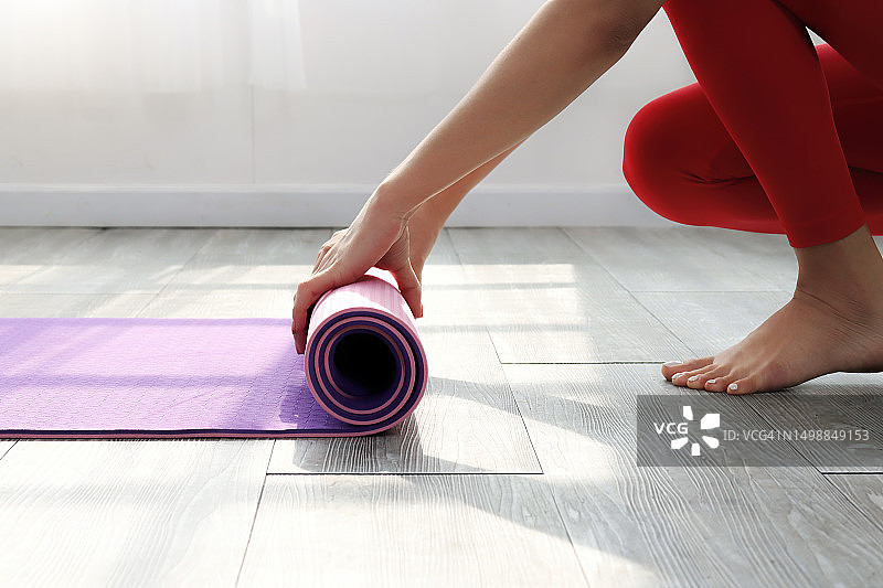 练习结束后卷起瑜伽垫的女人图片素材