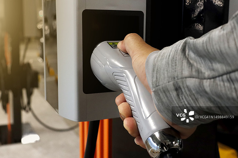 男人手持电动汽车充电枪图片素材