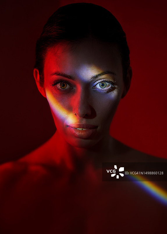红色霓虹灯下脸部彩虹光照女人肖像图片素材