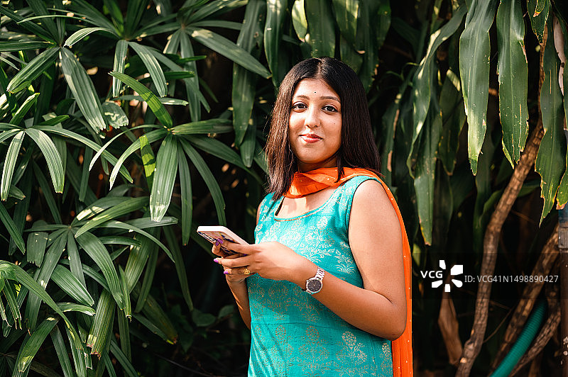 在公园使用智能手机的年轻印度女人图片素材