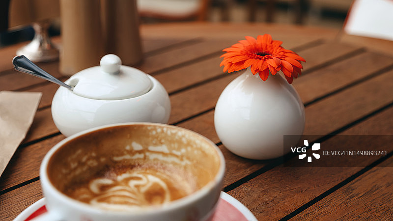 当地小咖啡馆木桌上大半杯卡布奇诺咖啡图片素材