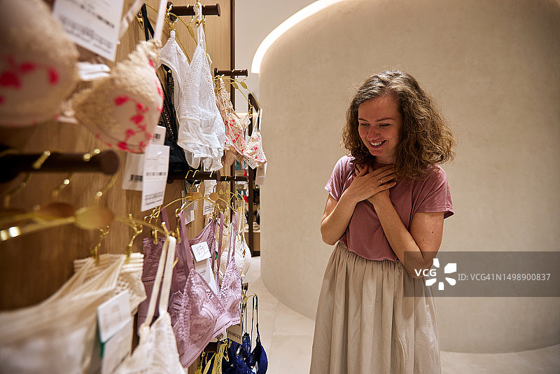 快乐的女人在商店里选择内衣图片素材