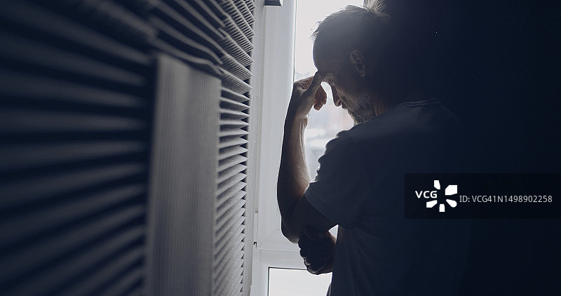 情绪低落的男人独自在黑暗的大厅里，用手揉搓脸图片素材