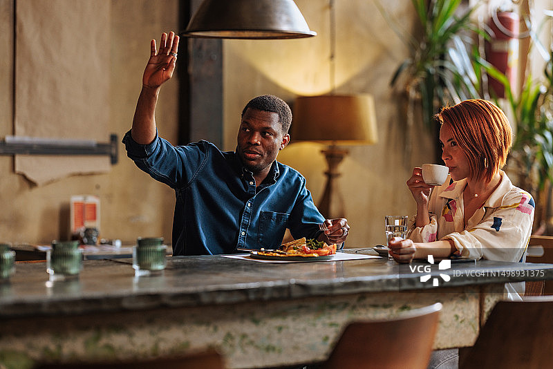 非裔男人和优雅的西班牙裔女人一起用餐并呼叫服务员图片素材