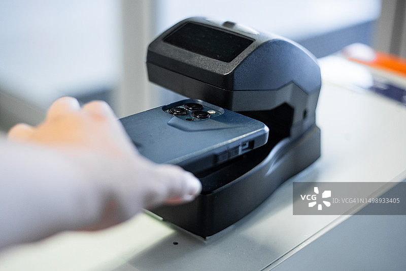 一位白人女性在机场办理登机手续，手持智能手机靠近票务扫描器图片素材