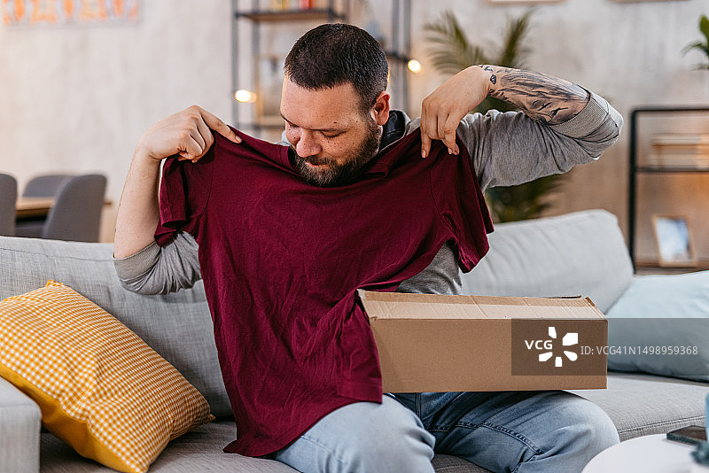 年轻男人拆开网上购买的包裹图片素材