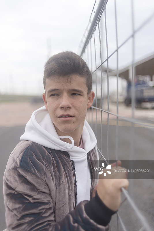 倚靠在城市栅栏上的年轻少年肖像图片素材