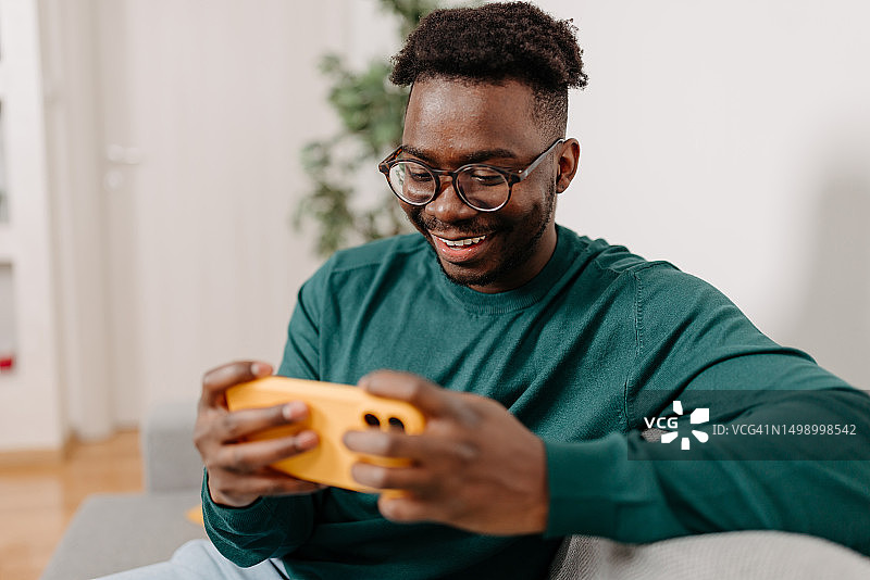 微笑的年轻男人在手机上探索手机游戏的刺激，发现快乐和娱乐图片素材