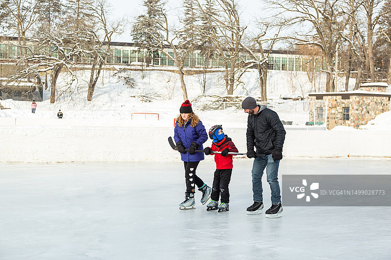 父亲和姐妹帮助男孩学习滑冰图片素材
