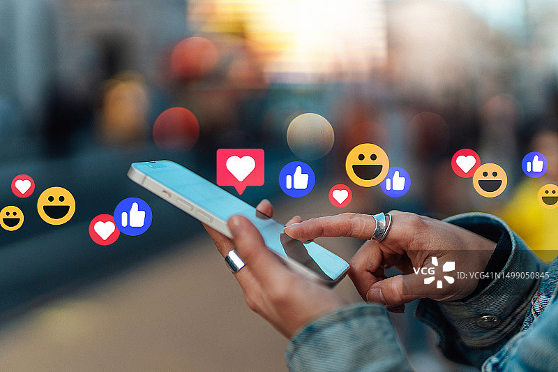 年轻的亚洲女性在城市街道上用智能手机查看社交媒体图片素材