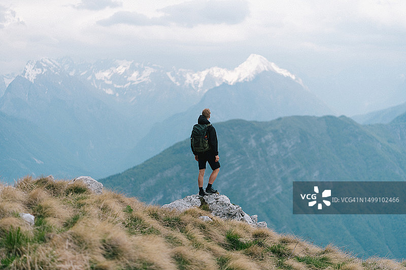 背包客站在深谷上方的岩石上向外看图片素材