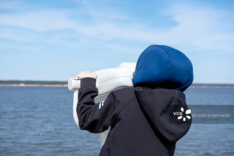 男孩在海边用望远镜观察美景图片素材