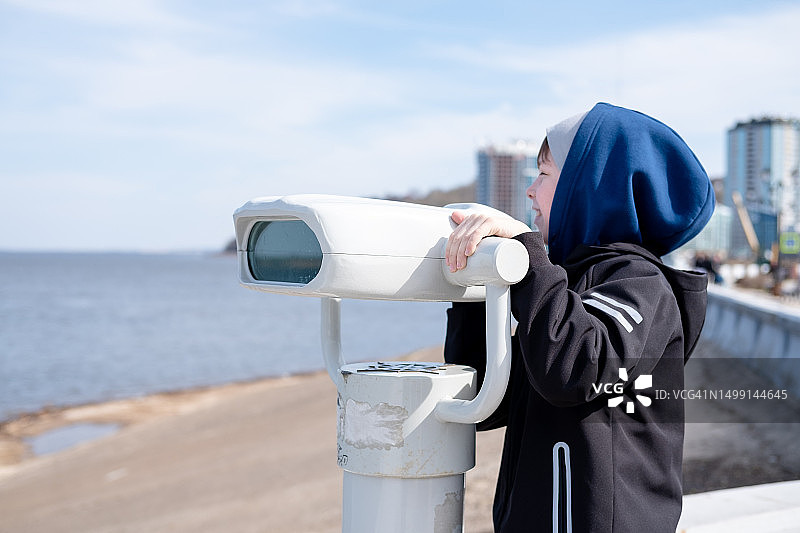 男孩在海边用望远镜观察美景图片素材