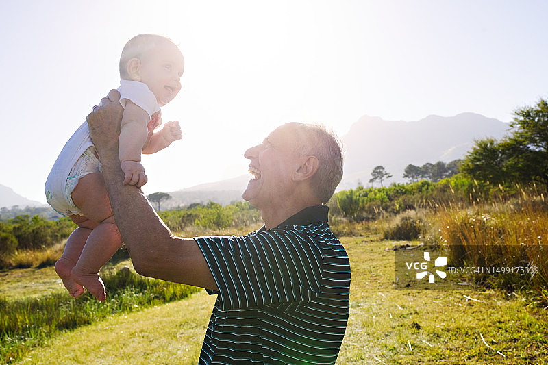 祖父举起微笑的孙子，镜头光晕图片素材