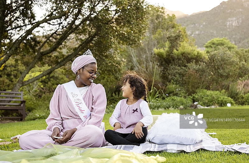 在公园里为待嫁新娘举办聚会，面带微笑的非洲裔女子和坐在她身边的小女孩图片素材