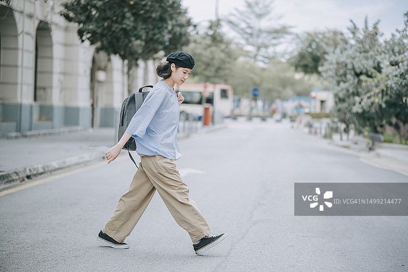 亚洲华人年轻女性在槟城老城过马路，手提包图片素材