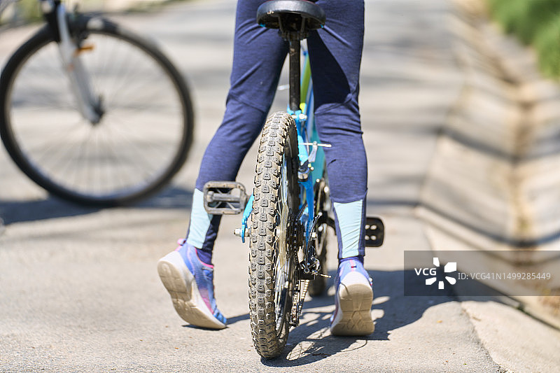 女孩在公园阳光下骑自行车背影图片素材