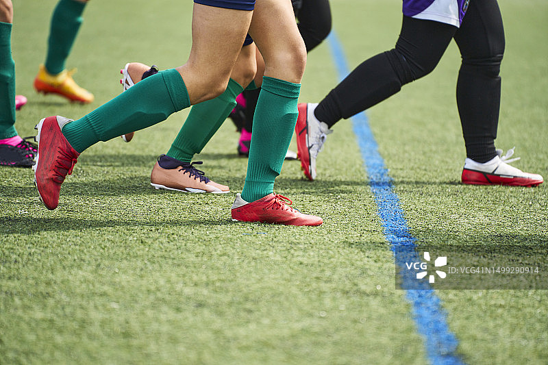 一群女孩在足球场上跑步练习的腿部特写，侧视图图片素材