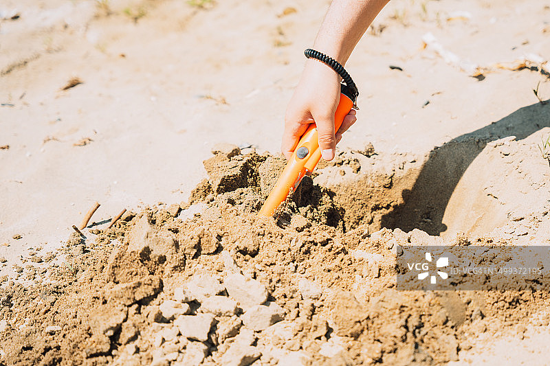 男子用手持金属探测器在沙滩上寻找珠宝图片素材