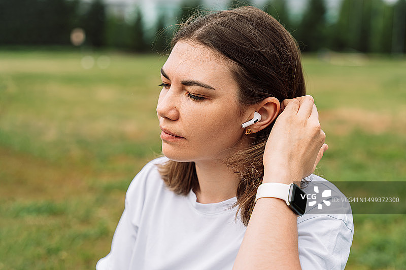 女人戴着无线耳机在户外听音乐图片素材