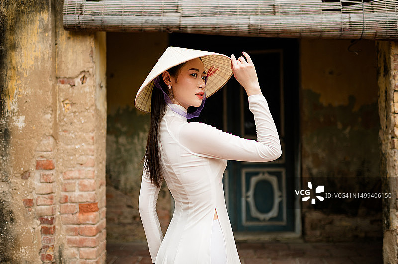 身穿白色传统奥黛和越南帽的快乐越南女孩图片素材
