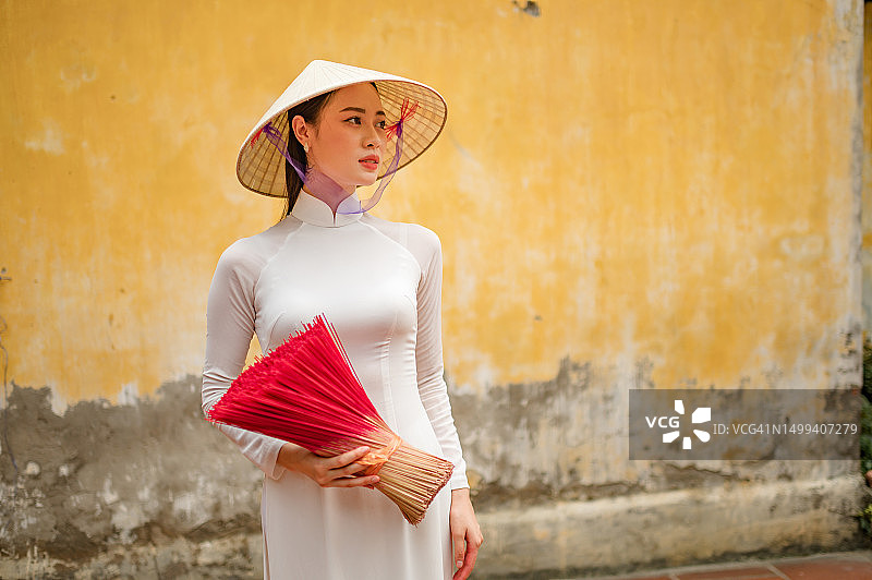 身穿白色传统奥黛和越南帽的快乐越南女孩图片素材