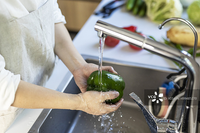 在厨房水槽里洗蔬菜的亚洲女人图片素材