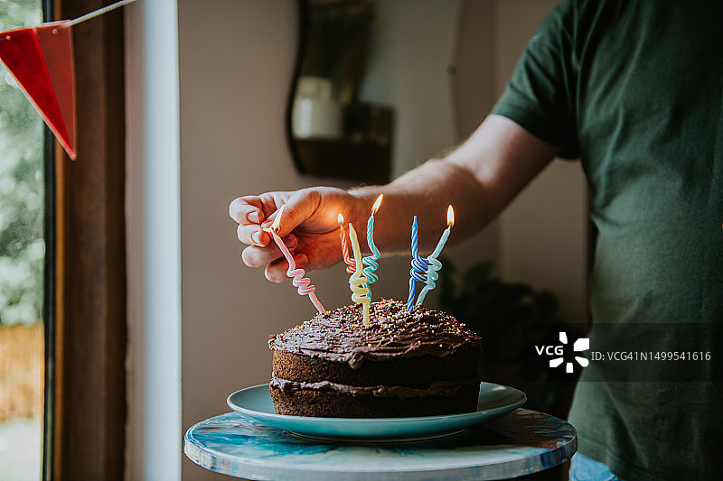 男人点燃生日蛋糕上的蜡烛图片素材