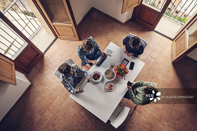 一家人使用现代移动设备，享用一些水果零食图片素材