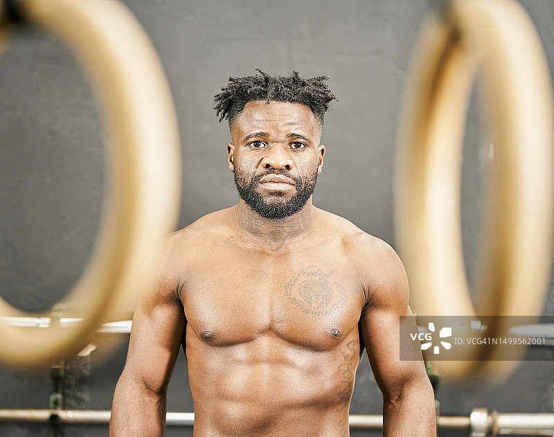 在健身房里看着镜头的健壮的深棕色男人正面肖像图片素材