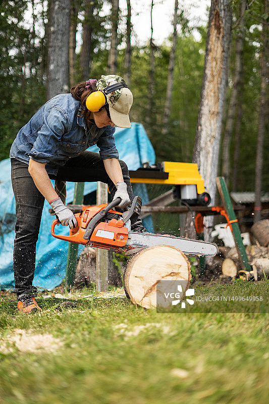 女人用电锯锯木头图片素材