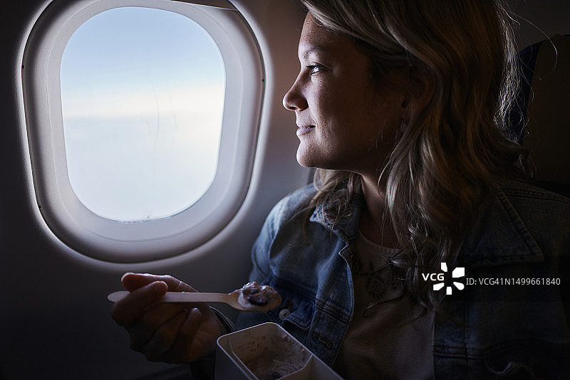 微笑的女人在飞机上吃零食图片素材
