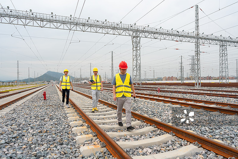 三名铁路工人在轨道上巡逻图片素材